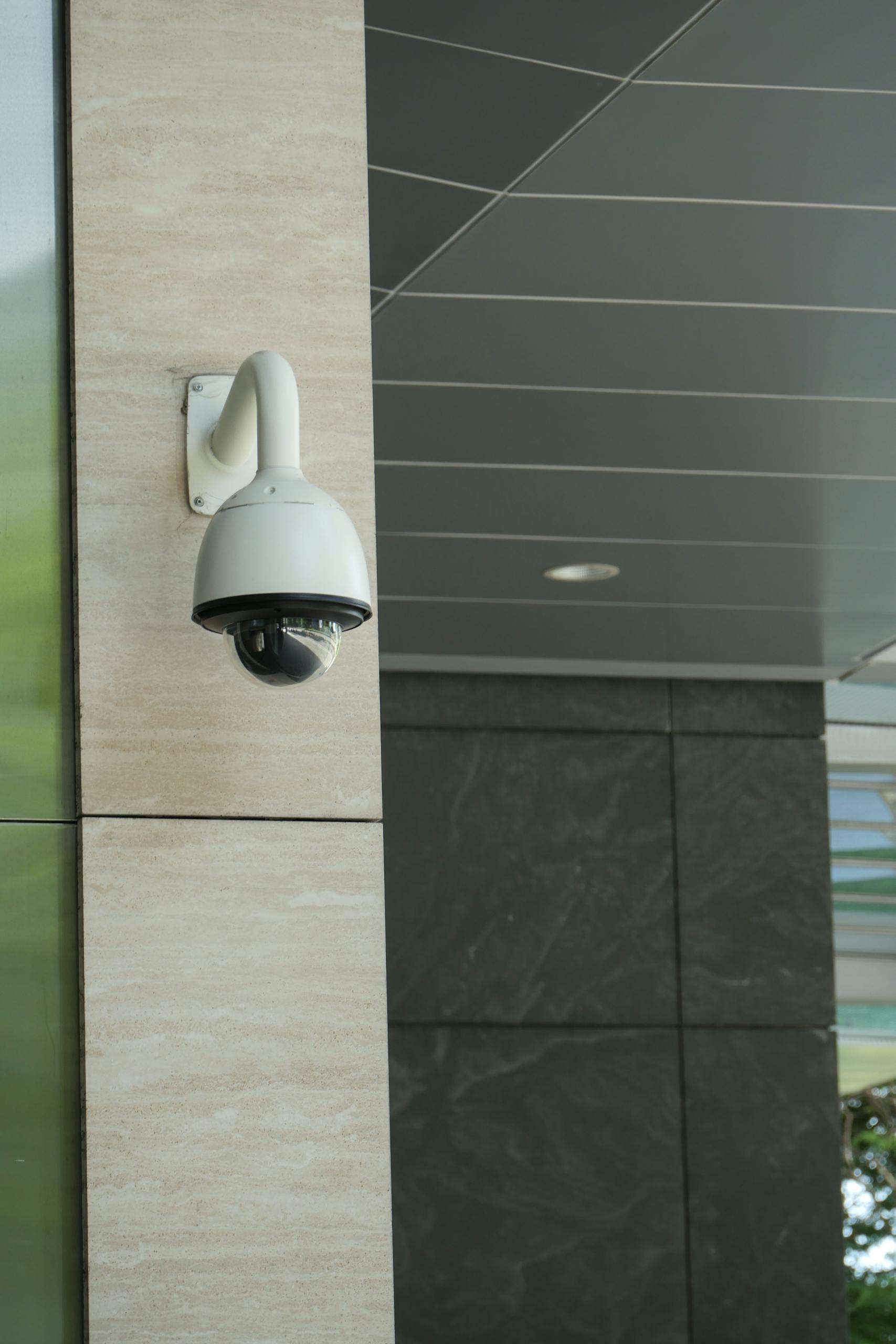Close-up of a mounted security camera on a modern building's exterior.